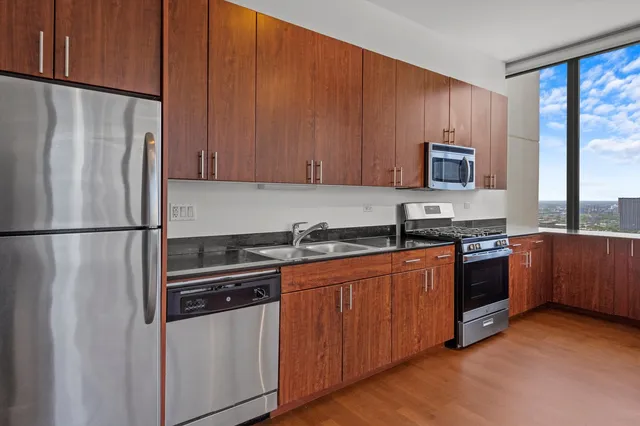 a kitchen with stainless steel appliances granite countertop a refrigerator a stove a sink and a microwave