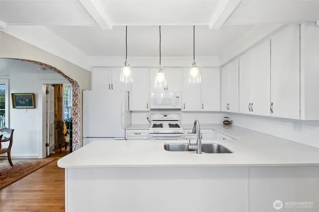 a kitchen that has a lot of white cabinets and stainless steel appliances
