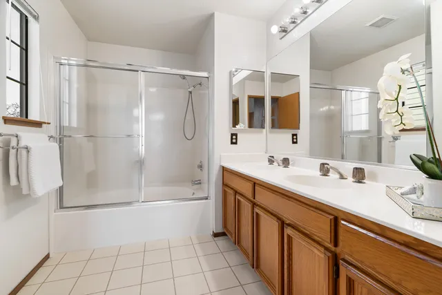 a bathroom with a double vanity sink a large mirror and shower