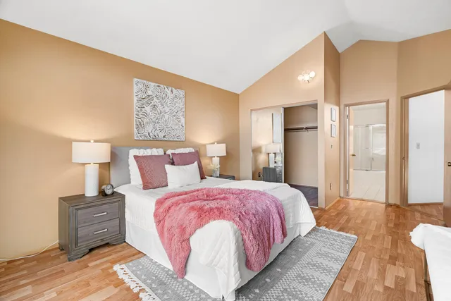 a spacious bedroom with a bed and wooden floor