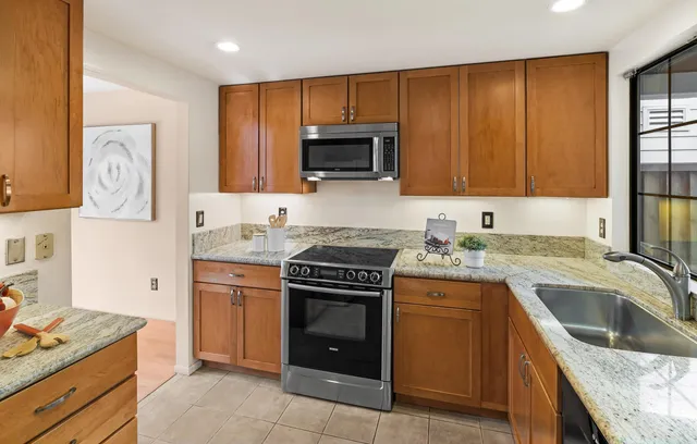 a kitchen with granite countertop a stove sink and cabinets