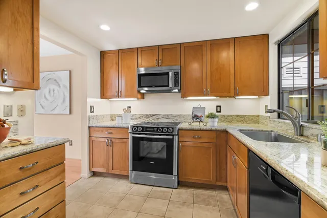 a kitchen with granite countertop wooden cabinets stainless steel appliances and a window