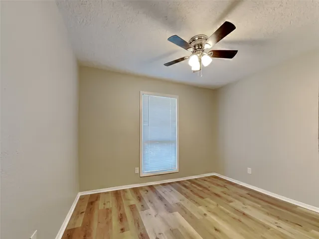 an empty room with a window and a ceiling fan