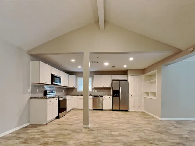 a kitchen with stainless steel appliances kitchen island granite countertop a stove top oven a refrigerator and white cabinets