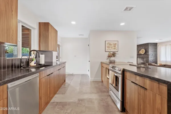 a large kitchen with stainless steel appliances a sink stove and cabinets