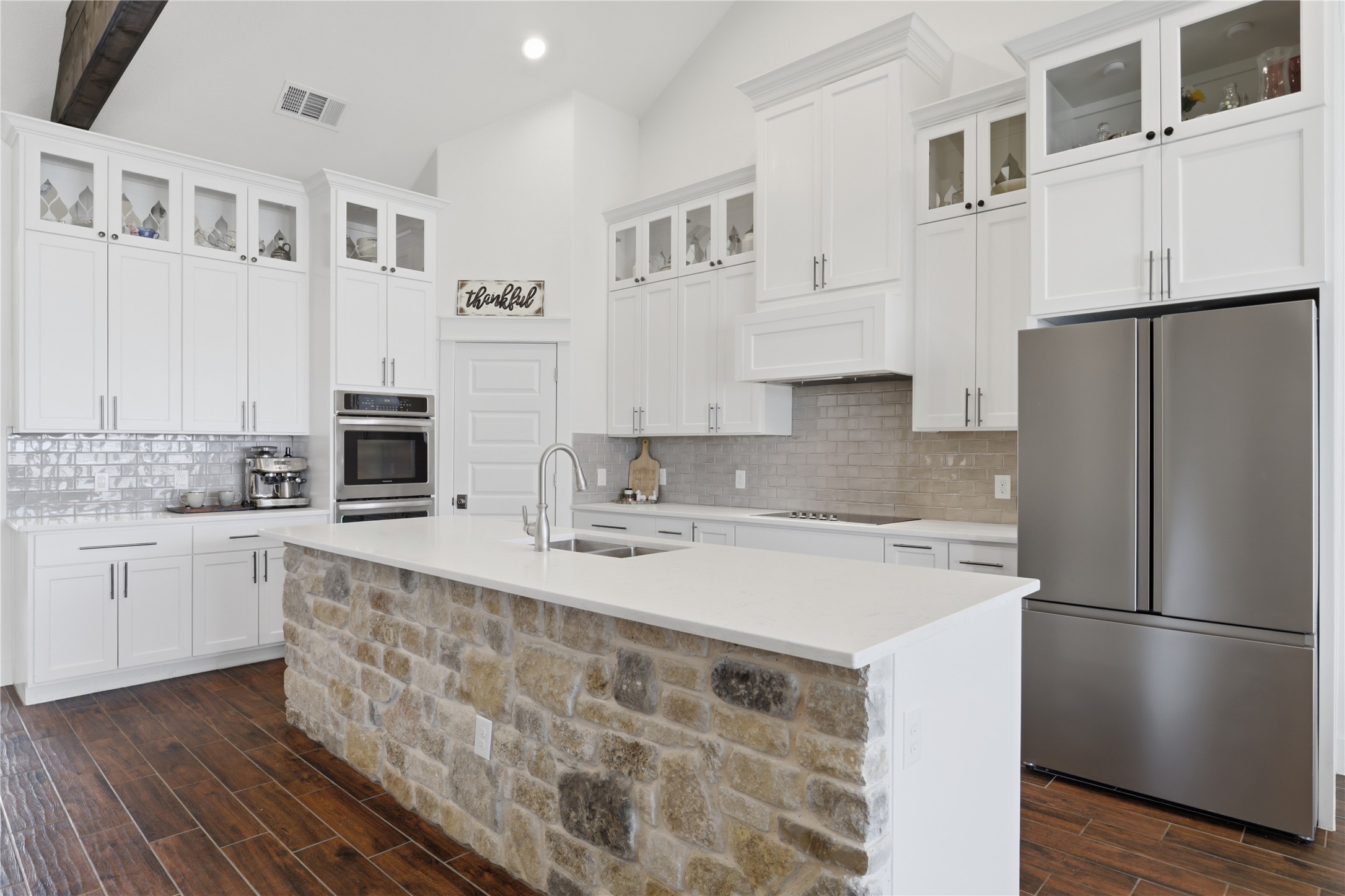 133 Greg Lane Jarrell, TX 76537 - Photo 8 of 24 Contemporary kitchen featuring a stone-clad island, white cabinetry, integrated stainless steel appliances, a subway tile backsplash, and wood-finish flooring