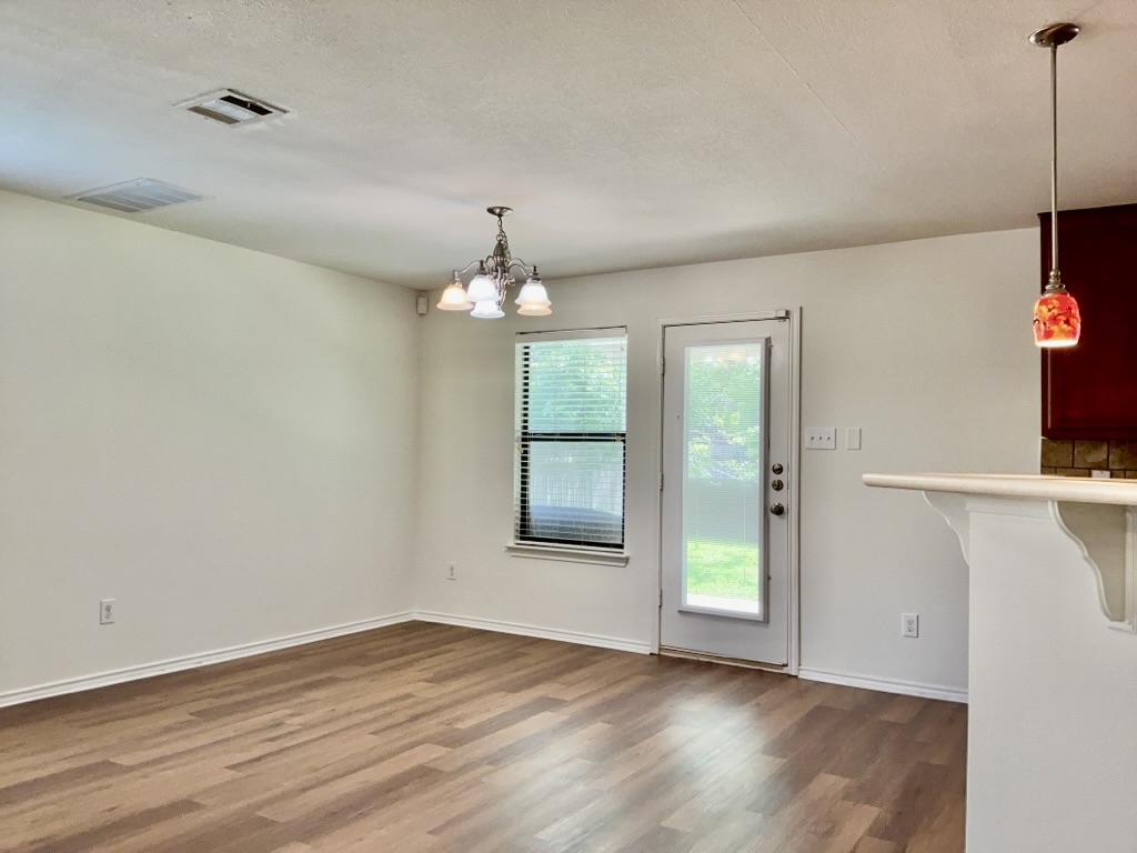 2242 Perkins Place Georgetown, TX 78626 - Photo 9 of 25 Dining area featuring wood-finish flooring, a contemporary chandelier, and a glass-paneled exterior door