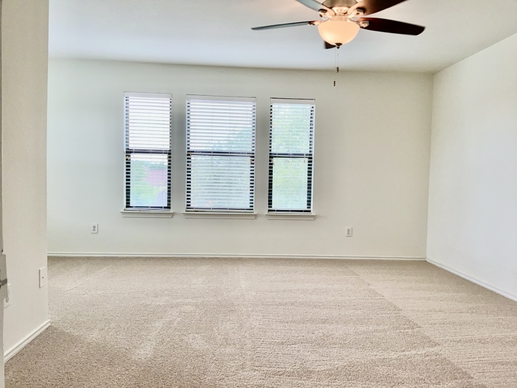 2242 Perkins Place Georgetown, TX 78626 - Photo 10 of 25 Room featuring three windows with horizontal blinds, neutral-toned wall paint, and ceiling fan with integrated lighting