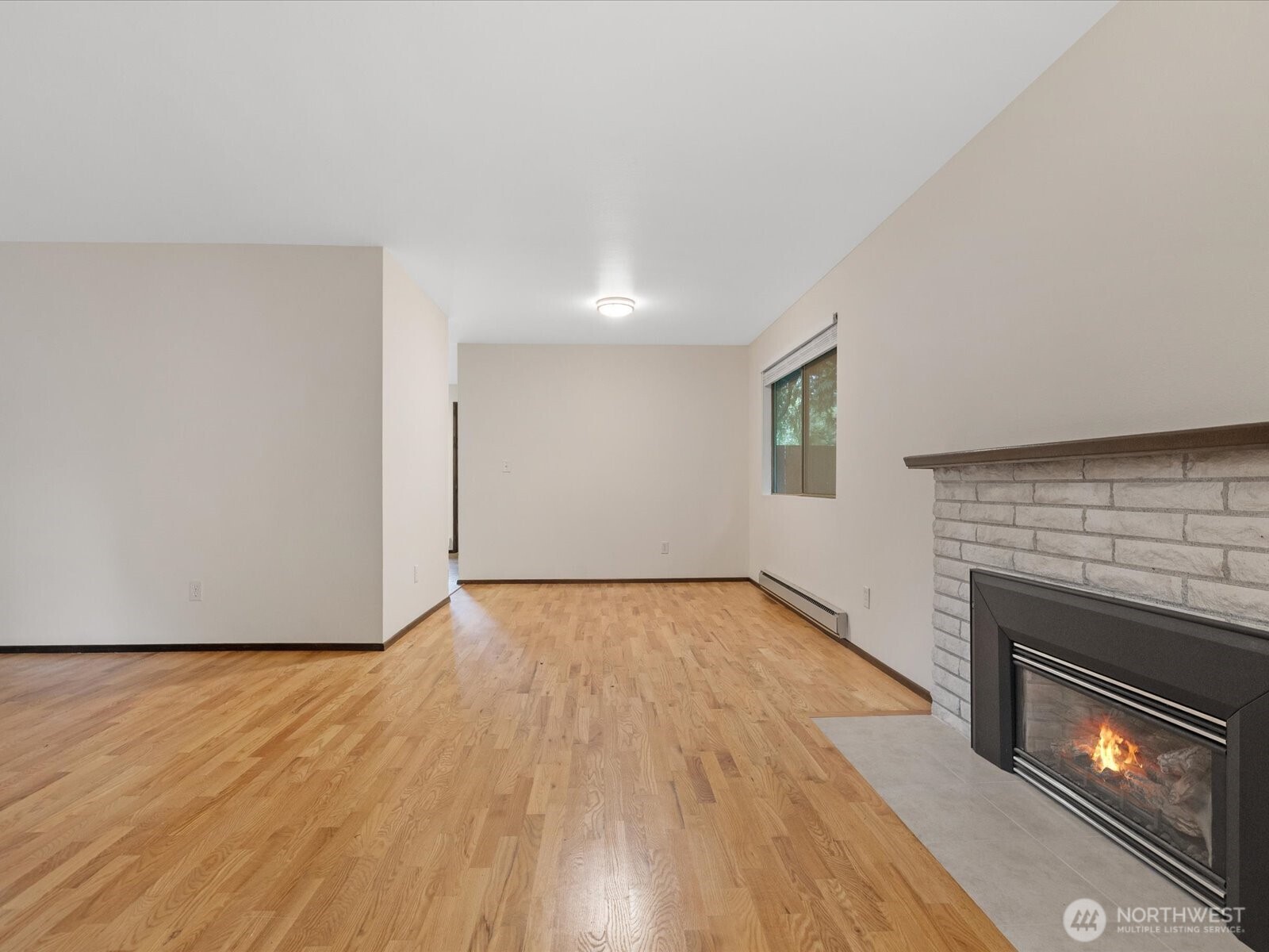 8506 192nd Street Southwest Edmonds, WA 98026 - Photo 12 of 37 a view of an empty room with wooden floor fireplace and a window