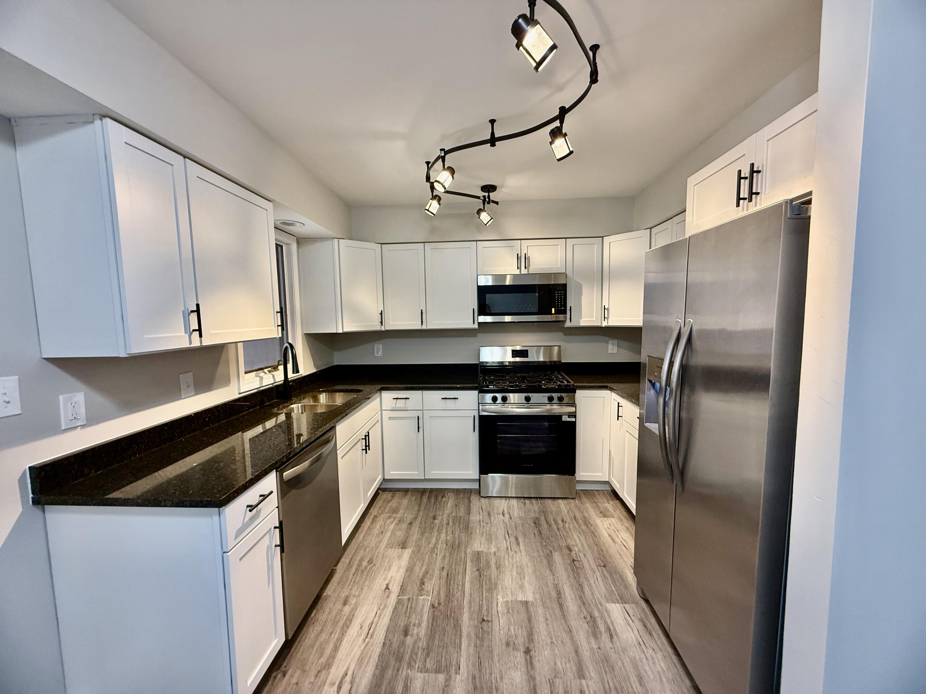 1962 Aspen Court Crown Point, IN 46307 - Photo 6 of 27 a kitchen with kitchen island granite countertop a refrigerator a sink dishwasher a stove and white cabinets with wooden floor