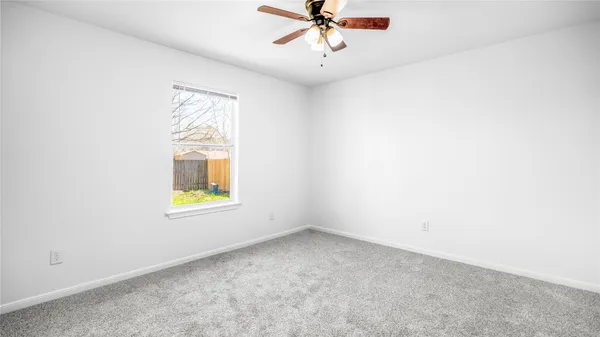 an empty room with a window and a ceiling fan
