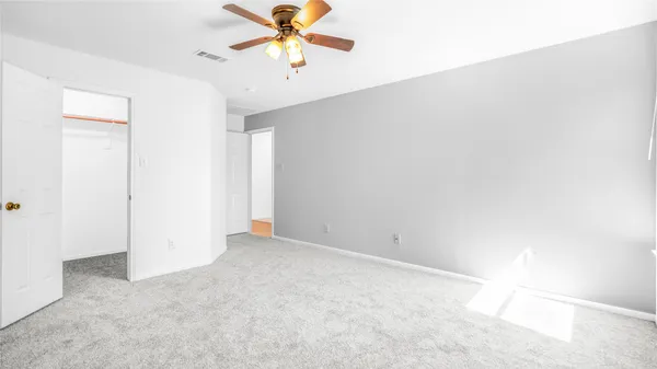 an empty room with a window and a fan