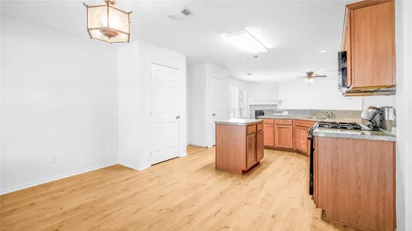 a kitchen with stainless steel appliances granite countertop a refrigerator a stove top oven and a sink with wooden floor