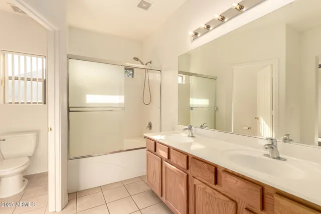 a spacious bathroom with a double vanity sink toilet mirror and