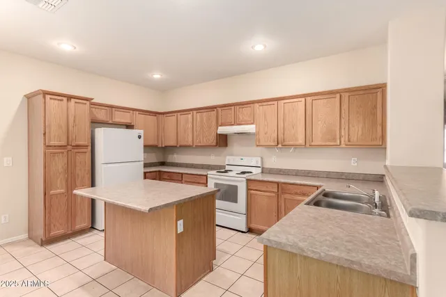 a kitchen with granite countertop a refrigerator a sink dishwasher and white cabinets next to a window