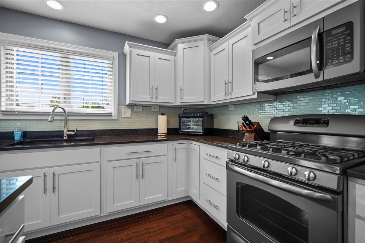 2321 Corrigan Way Normal, IL 61761 - Photo 12 of 33 a kitchen with stainless steel appliances granite countertop a sink a stove and microwave with wooden floor
