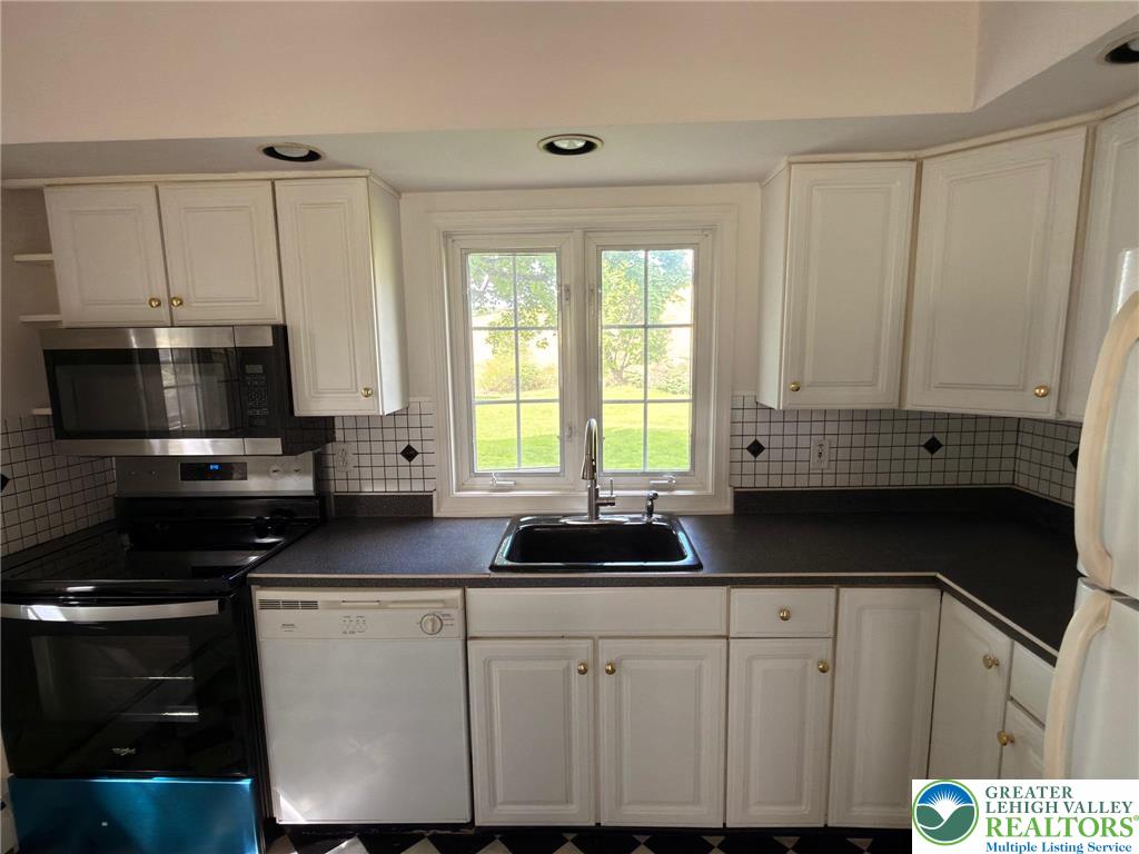 9751 Newtown Road, Unit B Breinigsville, PA 18031 - Photo 7 of 17 a kitchen with granite countertop white cabinets and black appliances