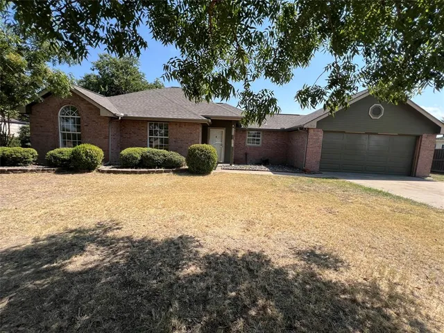 a view of house with yard and a large tree