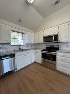 a kitchen with granite countertop a sink cabinets and stainless steel appliances