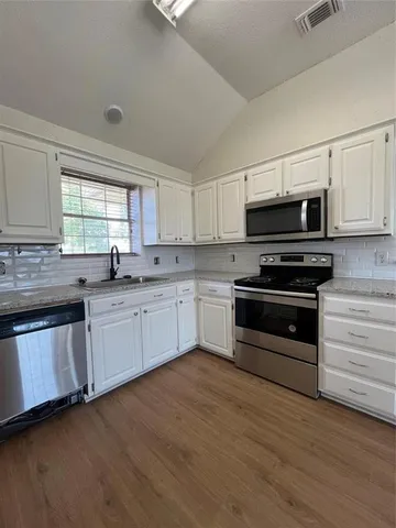 a kitchen with granite countertop a sink cabinets and stainless steel appliances