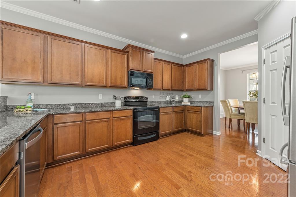 116 Annatto Way Tega Cay, SC 29708 - Photo 13 of 36 a kitchen with granite countertop wooden cabinets a sink a stove a window and stainless steel appliances