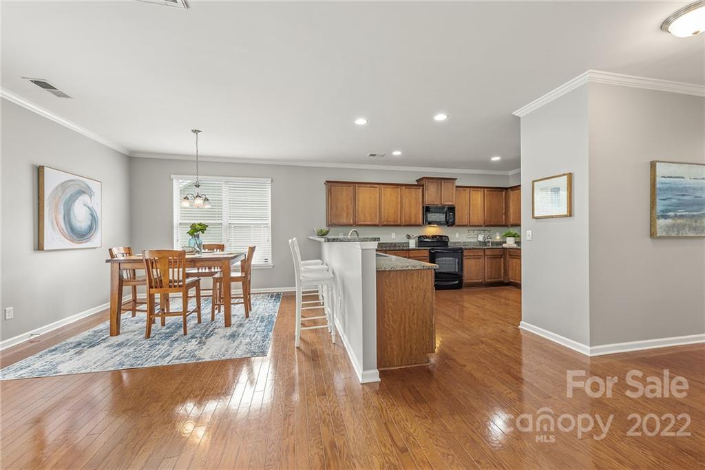 116 Annatto Way Tega Cay, SC 29708 - Photo 9 of 36 a kitchen with stainless steel appliances granite countertop a refrigerator a stove top oven a dining table and chairs with wooden floor