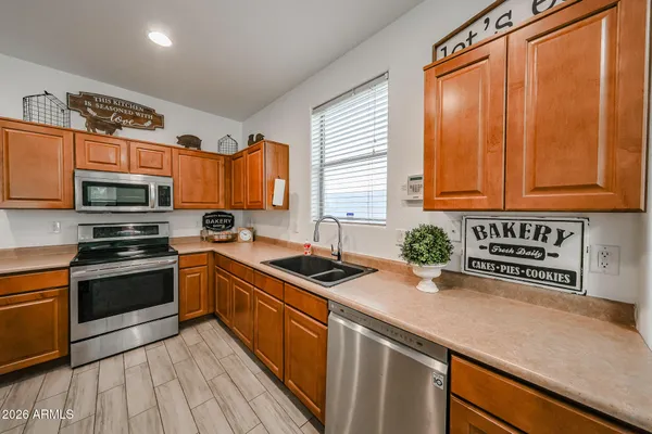 a kitchen with stainless steel appliances a sink dishwasher a stove a microwave oven with cabinets and wooden floor