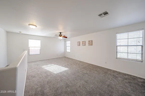 an empty room with windows and chandelier fan