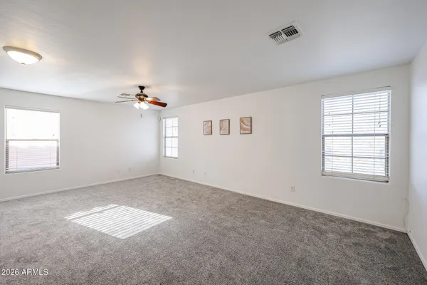 an empty room with chandelier fan and windows