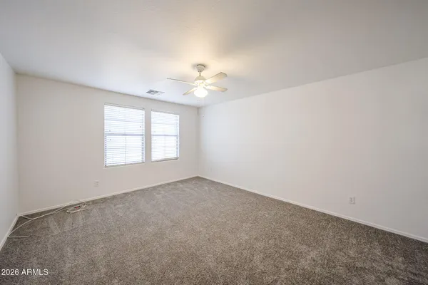 an empty room with windows and ceiling fan