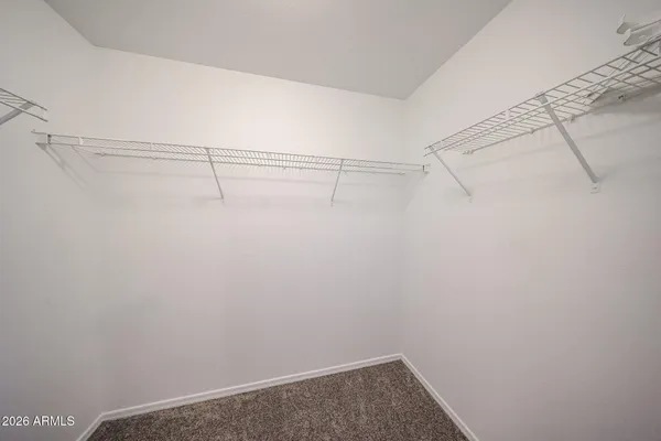 an empty room with a chandelier fan and windows