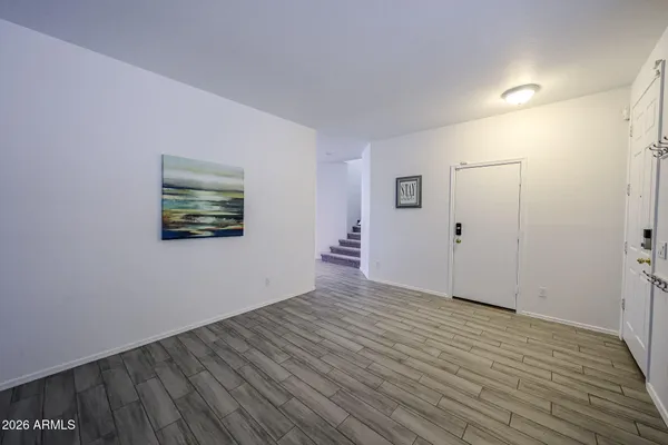 a view of an empty room with wooden floor and a window
