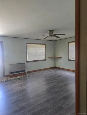 a view of an empty room with window and wooden floor