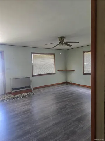 a view of an empty room with window and wooden floor