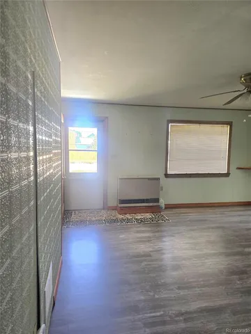 a view of a refrigerator in kitchen and an empty room
