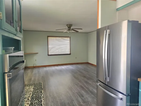 a view of a refrigerator in kitchen and an empty room