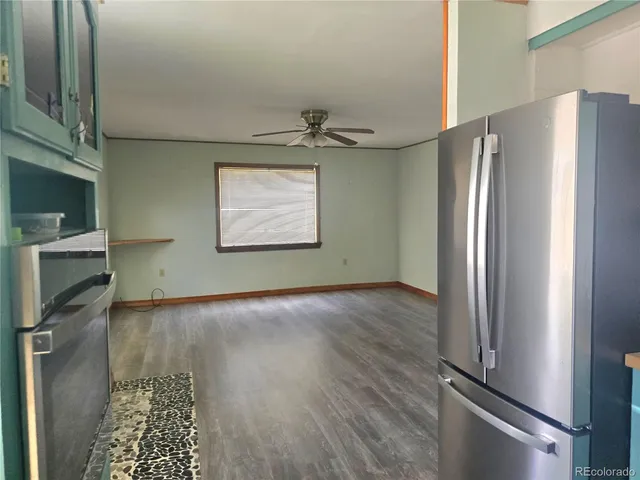 a view of a refrigerator in kitchen and an empty room