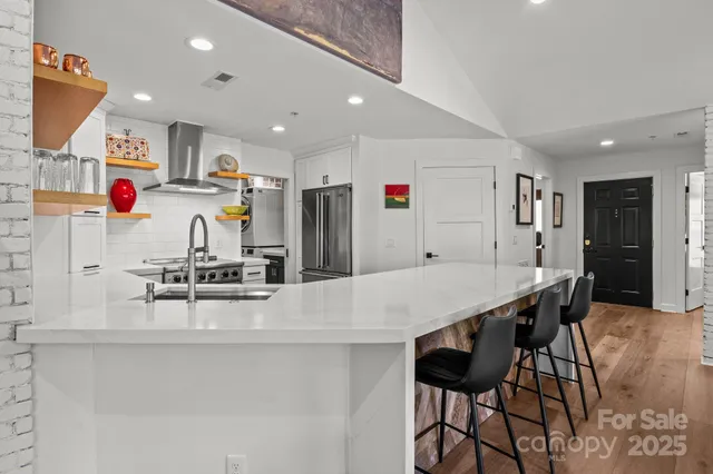 a kitchen with stainless steel appliances kitchen island granite countertop a dining table chairs and white cabinets