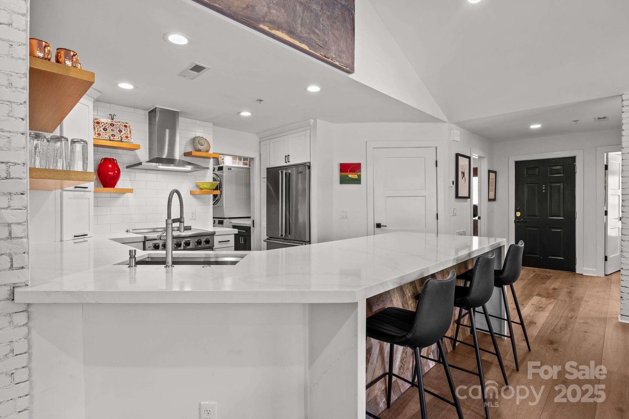 950 Jetton Street, Unit 3 Davidson, NC 28036 - Photo 12 of 29 a kitchen with stainless steel appliances kitchen island granite countertop a dining table chairs and white cabinets