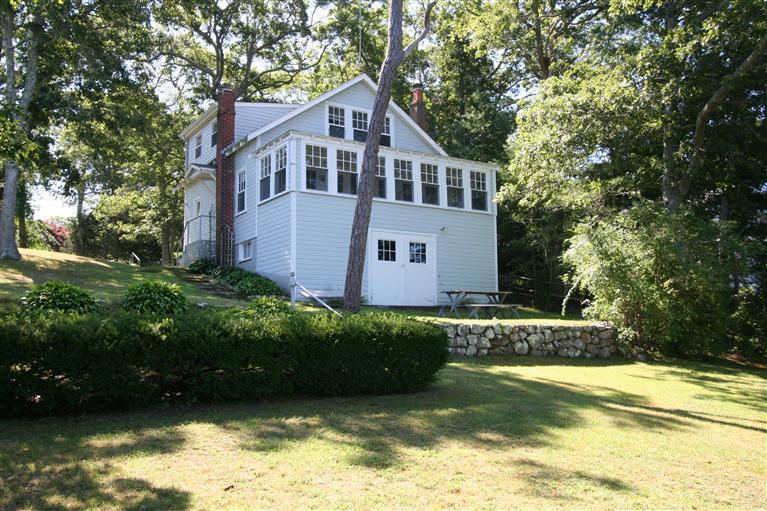 a front view of a house with a yard and large trees