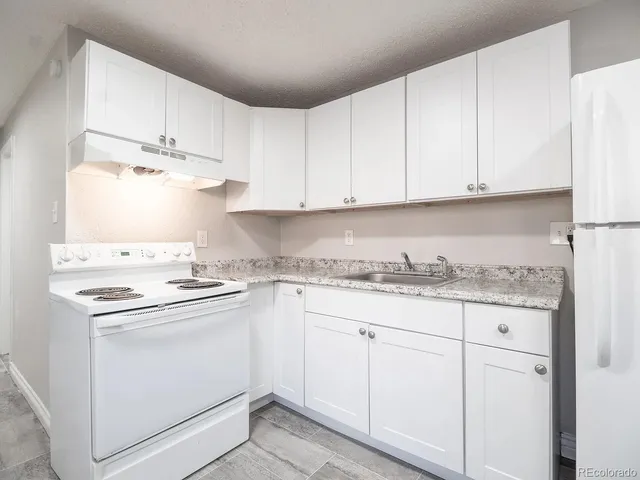 a kitchen with granite countertop white cabinets and white appliances