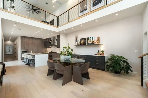 a kitchen with stainless steel appliances kitchen island granite countertop a refrigerator a stove a sink a dining table and chairs with wooden floor