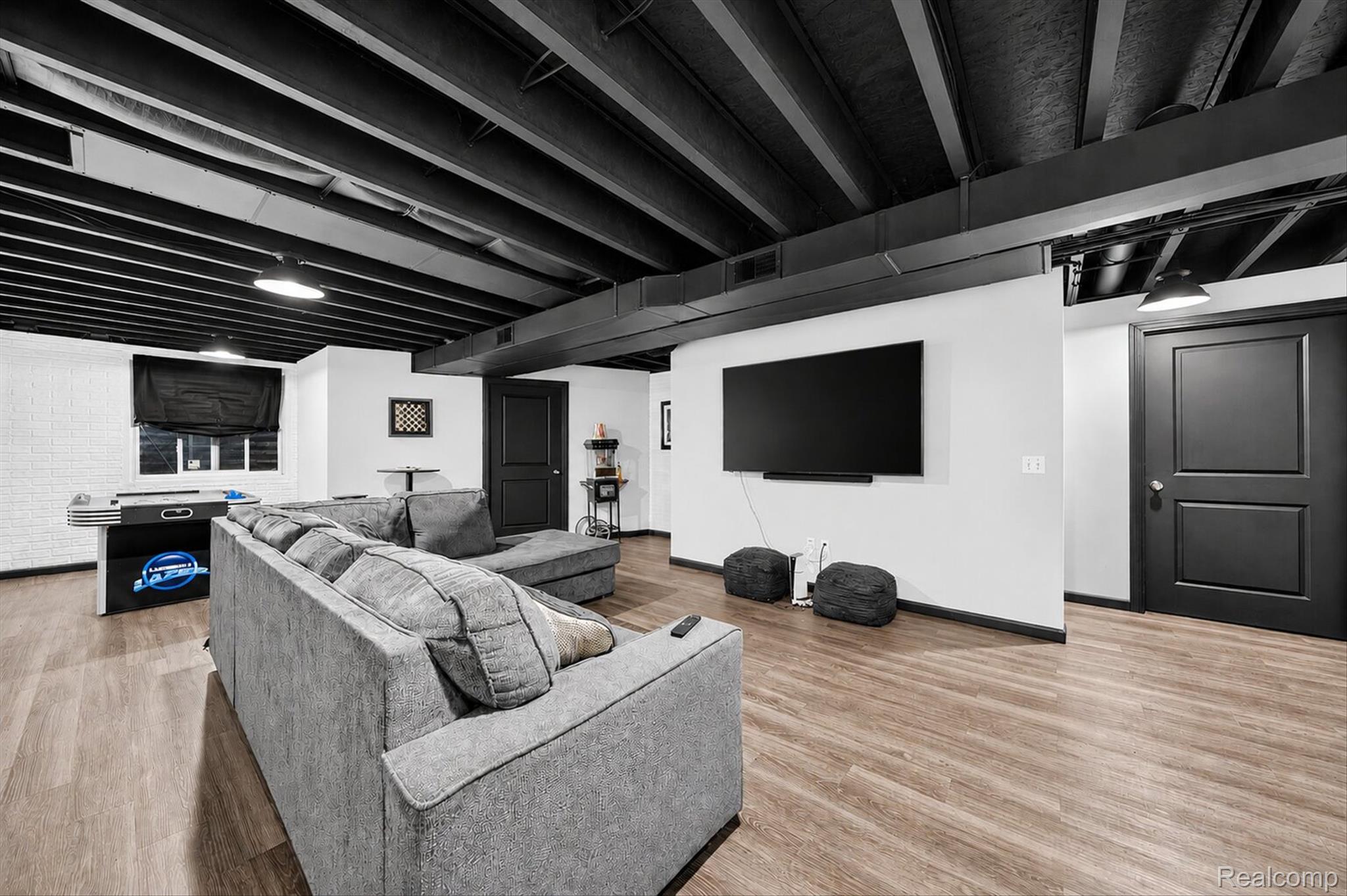 5382 Rural Terrace Waterford, MI 48329 - Photo 28 of 35 Spacious recreation room featuring wood-finish flooring, exposed black ceiling beams, and white painted walls