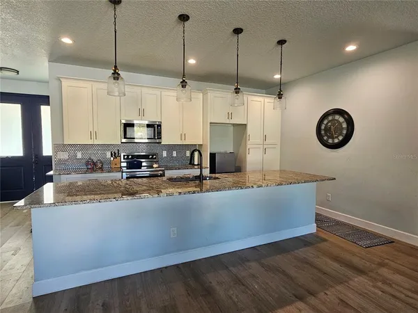 a large kitchen with stainless steel appliances granite countertop a sink a stove a oven a kitchen island with wooden floor