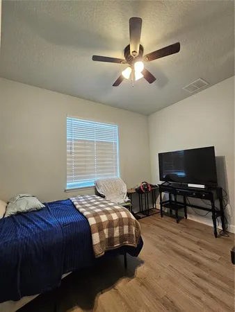 a bedroom with a bed a dresser and a flat screen tv