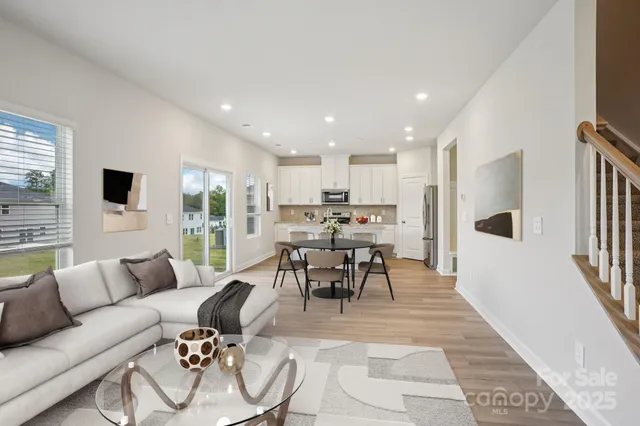 a living room with furniture kitchen view and a large window