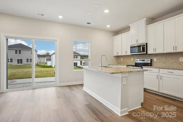a kitchen with granite countertop a stove a sink and a microwave