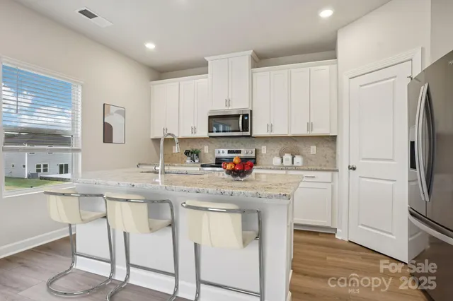 a kitchen with stainless steel appliances granite countertop a refrigerator and a stove top oven