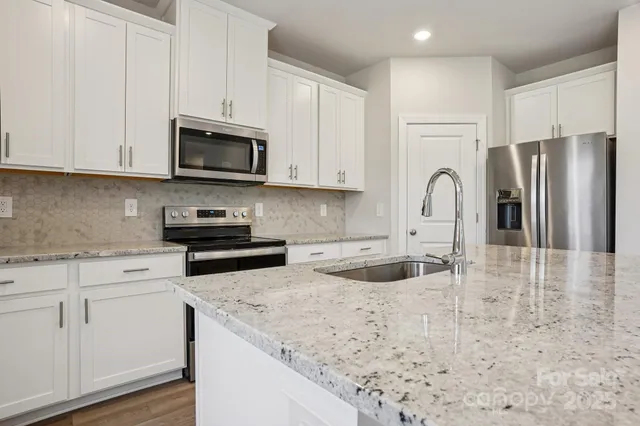 a kitchen with stainless steel appliances granite countertop a sink a stove a refrigerator and cabinets
