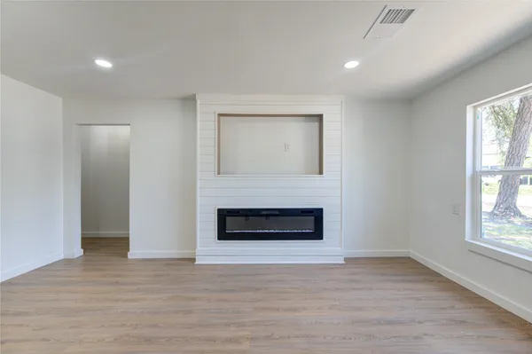 an empty room with wooden floor fireplace and windows